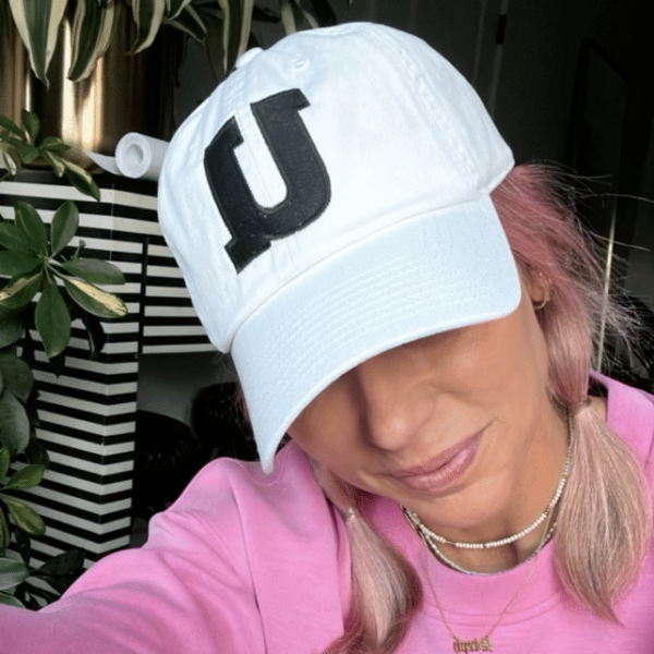 An Unleashed Health and Fitness hat in white with a black u on the front.