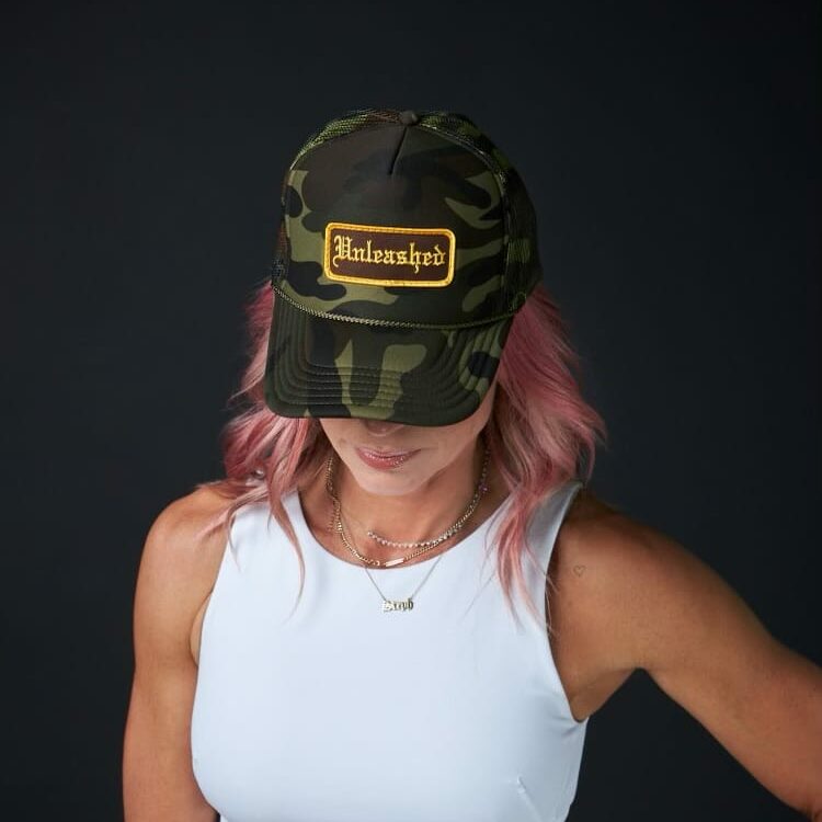 An Unleashed Health and Fitness branded camo trucker hat.